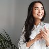 Portrait,Of,Attractive,Asian,Woman,Looking,Outside,Window,And,Smiling